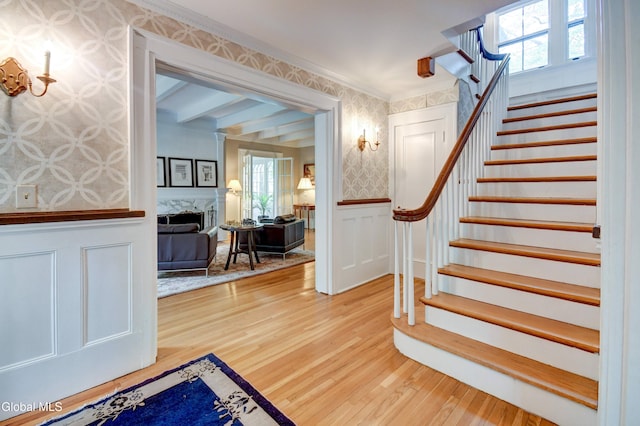 1171 Lowell Rd, Schenectady, NY 12308 - stairway featuring wallpapered walls, wood finished floors, wainscoting, a decorative wall, and a premium fireplace