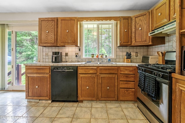 1927 Berne Altamont Rd, Altamont, NY 12009 - kitchen with black dishwasher, gas stove, under cabinet range hood, tasteful backsplash, and brown cabinets