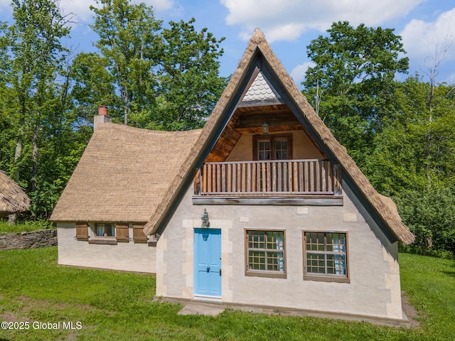 372 Jones Hill Rd, Jefferson, NY 12093 - back of house with a balcony, stucco siding, a lawn, and a chimney