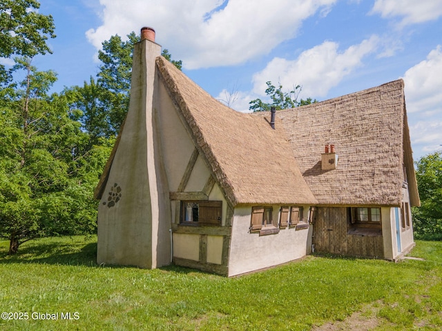 372 Jones Hill Rd, Jefferson, NY 12093 - back of house with a chimney, a yard, and stucco siding