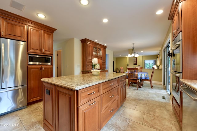 14 Friar Tuck Ct, Clifton Park, NY 12065 - kitchen with stainless steel appliances, brown cabinetry, light stone countertops, a kitchen island, and recessed lighting