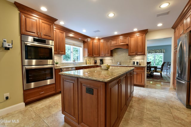 14 Friar Tuck Ct, Clifton Park, NY 12065 - kitchen featuring stainless steel appliances, brown cabinetry, light stone counters, plenty of natural light, and recessed lighting