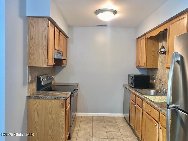 2059 Rosedale Way, Guilderland, NY 12303 - kitchen featuring stainless steel appliances, under cabinet range hood, decorative backsplash, dark countertops, and brown cabinets