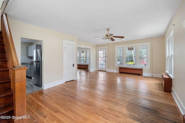 1707 Helderberg Trl, Berne, NY 12023 - unfurnished living room with radiator heating unit, light wood-style flooring, stairway, and a ceiling fan