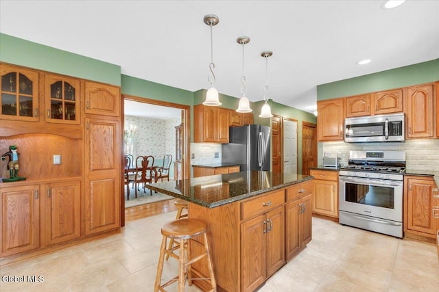630 Salvia Ln, Guilderland, NY 12303 - kitchen featuring appliances with stainless steel finishes, decorative backsplash, a kitchen island, dark stone counters, and a kitchen bar