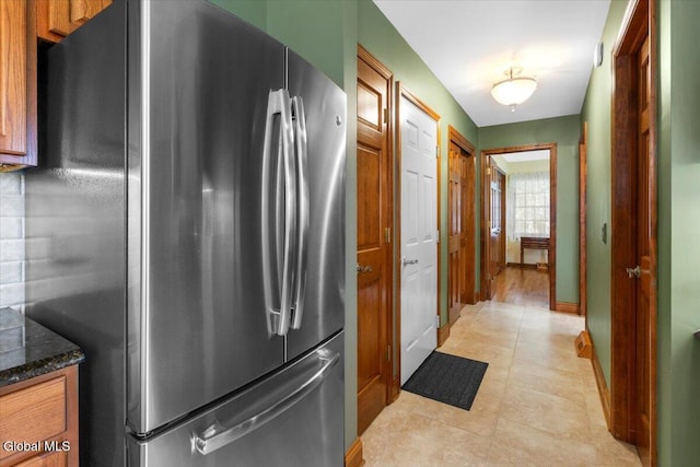 630 Salvia Ln, Guilderland, NY 12303 - kitchen featuring freestanding refrigerator, brown cabinetry, dark stone countertops, and light tile patterned floors