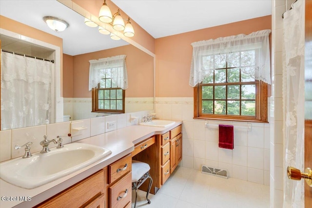 630 Salvia Ln, Guilderland, NY 12303 - full bathroom with tile walls, healthy amount of natural light, double vanity, wainscoting, and tile patterned flooring