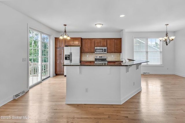 21 Beacon Dr, Colonie, NY 12189 - kitchen with stainless steel appliances, a chandelier, a breakfast bar area, light wood-style floors, and recessed lighting