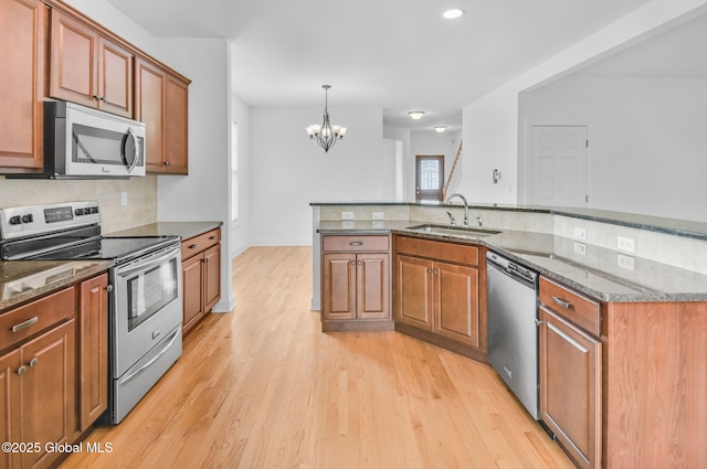 21 Beacon Dr, Colonie, NY 12189 - kitchen with stainless steel appliances, light wood-style flooring, a chandelier, backsplash, and dark stone counters
