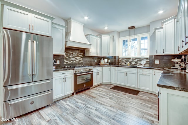 2794 W Lydius St, Schenectady, NY 12306 - kitchen featuring premium appliances, custom range hood, dark countertops, light wood-style floors, and decorative backsplash