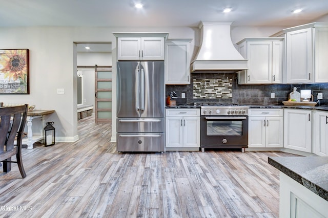 2794 W Lydius St, Schenectady, NY 12306 - kitchen with stainless steel appliances, custom exhaust hood, a barn door, light wood-type flooring, and tasteful backsplash