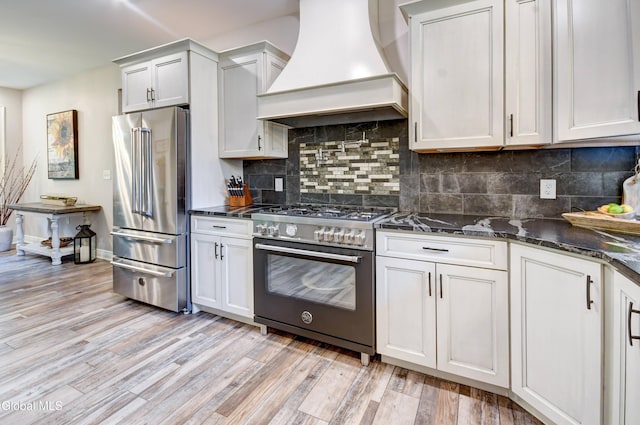 2794 W Lydius St, Schenectady, NY 12306 - kitchen featuring premium appliances, custom range hood, light wood-style flooring, backsplash, and dark stone counters