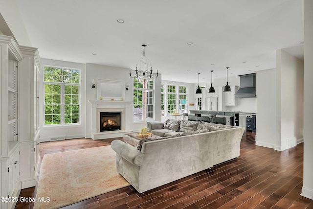 13 Bridlewood Loop, Clifton Park, NY 12148 - living area featuring dark wood finished floors, a warm lit fireplace, and a chandelier
