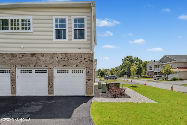 606 Vly Pointe Dr, Niskayuna, NY 12309 - view of side of property with brick siding, asphalt driveway, a yard, and a garage