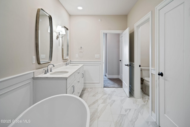 606 Vly Pointe Dr, Niskayuna, NY 12309 - full bathroom with marble look tile flooring, double vanity, a freestanding tub, a wainscoted wall, and a decorative wall