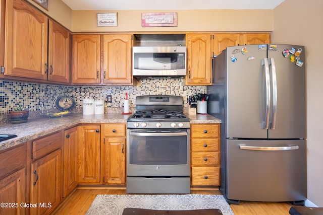 99 Fiddlers Ln, Colonie, NY 12110 - kitchen featuring appliances with stainless steel finishes, light wood-style flooring, tasteful backsplash, and brown cabinetry