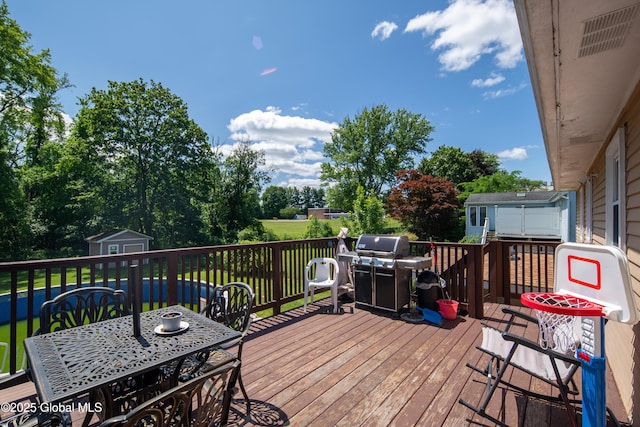 99 Fiddlers Ln, Colonie, NY 12110 - wooden terrace featuring a storage shed, grilling area, outdoor dining area, and view of wooded area