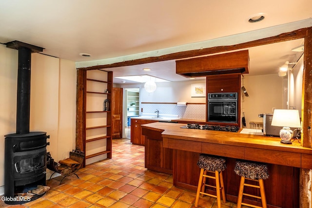 203 Center Rd, White Creek, NY 12057 - kitchen with butcher block counters, black appliances, open shelves, a wood stove, and a kitchen breakfast bar