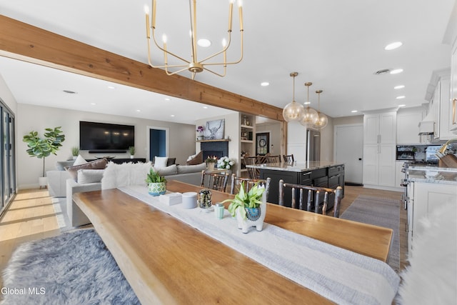 55 Trinity Rock Rd, Lake George, NY 12845 - dining room with recessed lighting, a chandelier, light wood-type flooring, a warm lit fireplace, and beamed ceiling