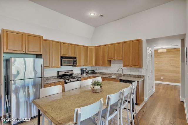 8 Trailside Dr Unit B10, Hunter, NY 12442 - kitchen featuring stainless steel appliances, light wood finished floors, high vaulted ceiling, light stone counters, and decorative backsplash