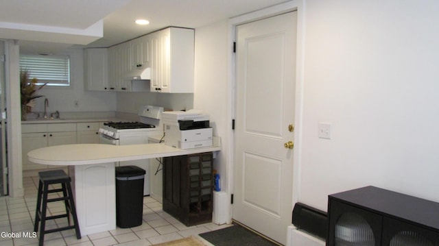 32 Winnie St, Albany, NY 12208 - kitchen featuring white gas stove, under cabinet range hood, a kitchen bar, a peninsula, and light tile patterned flooring