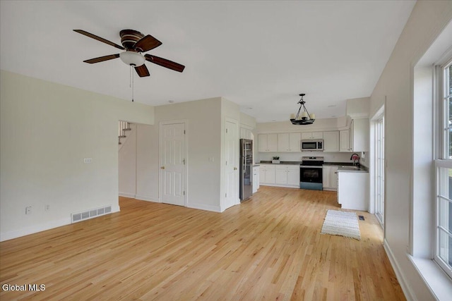 3 Lucille Ln, Malta, NY 12019 - unfurnished living room featuring light wood-type flooring, ceiling fan, and a chandelier