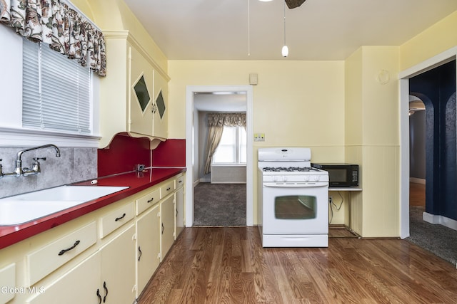 1633 Chrisler Ave, Schenectady, NY 12303 - kitchen featuring white gas range, black microwave, wood finished floors, and backsplash