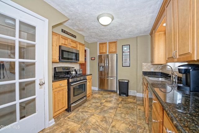 2834 Halsey Dr, Schenectady, NY 12304 - kitchen featuring stainless steel appliances, tasteful backsplash, dark stone counters, a textured ceiling, and dark stone finish flooring