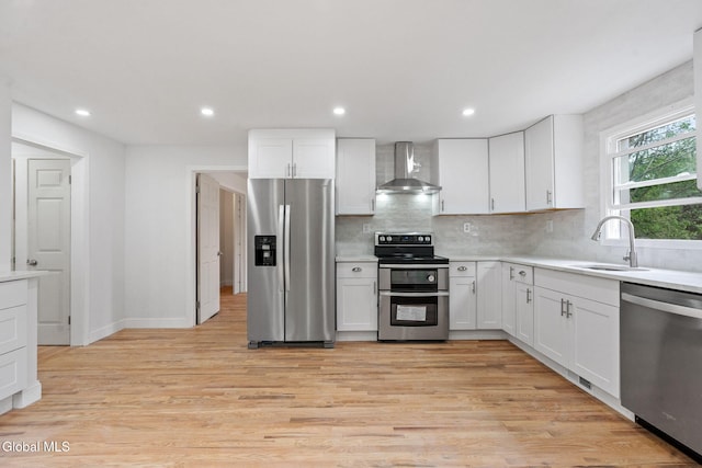 479 Albany Shaker Rd, Colonie, NY 12211 - kitchen featuring appliances with stainless steel finishes, wall chimney exhaust hood, decorative backsplash, white cabinetry, and recessed lighting