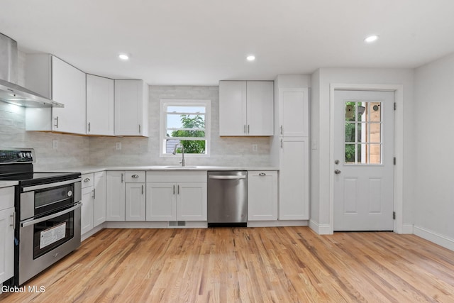 479 Albany Shaker Rd, Colonie, NY 12211 - kitchen featuring appliances with stainless steel finishes, wall chimney range hood, light wood finished floors, light countertops, and recessed lighting