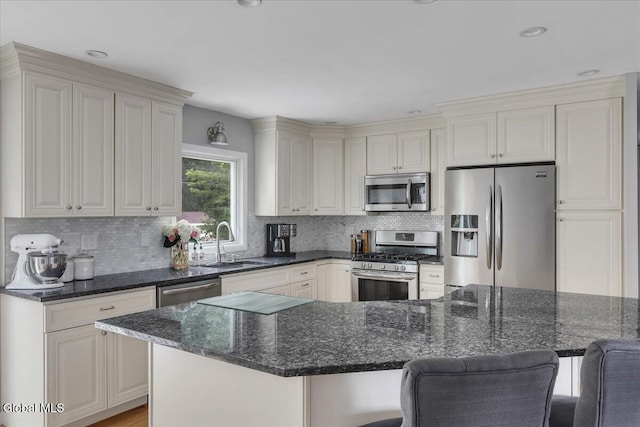 33 Comely Ln, Colonie, NY 12110 - kitchen featuring appliances with stainless steel finishes, a kitchen breakfast bar, tasteful backsplash, dark stone counters, and recessed lighting