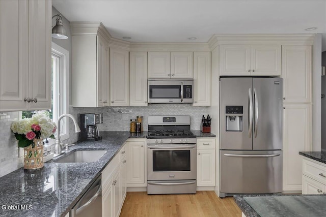 33 Comely Ln, Colonie, NY 12110 - kitchen with stainless steel appliances, decorative backsplash, dark stone counters, light wood-style floors, and white cabinetry