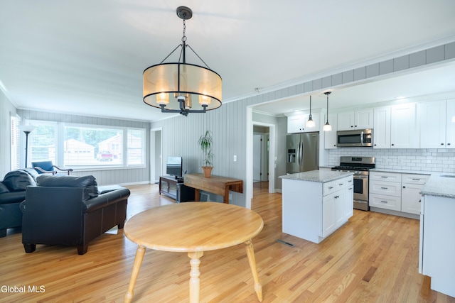 98 Meadowbrook Rd, Saratoga Springs, NY 12866 - kitchen featuring stainless steel appliances, crown molding, open floor plan, a center island, and light wood-type flooring