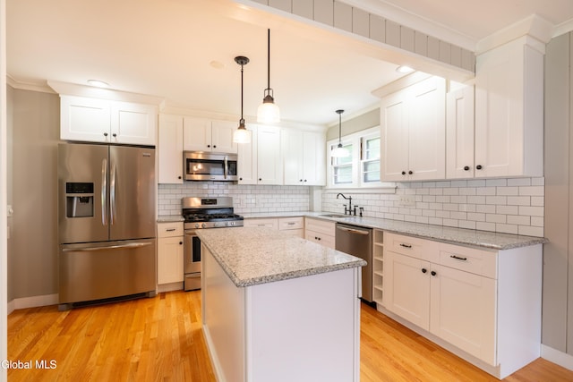 98 Meadowbrook Rd, Saratoga Springs, NY 12866 - kitchen featuring appliances with stainless steel finishes, light wood-type flooring, ornamental molding, white cabinetry, and a center island