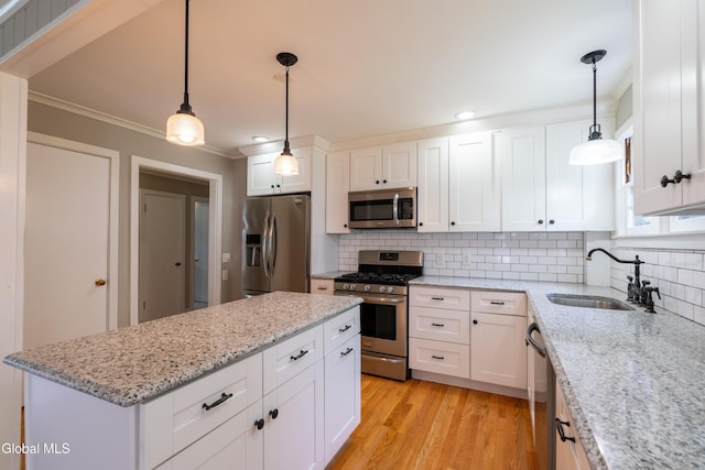 98 Meadowbrook Rd, Saratoga Springs, NY 12866 - kitchen featuring appliances with stainless steel finishes, tasteful backsplash, a kitchen island, white cabinets, and crown molding