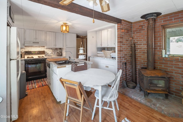 5530 State Highway 30a, Charleston, NY 12066 - kitchen with range with gas cooktop, extractor fan, a wood stove, and wood finished floors