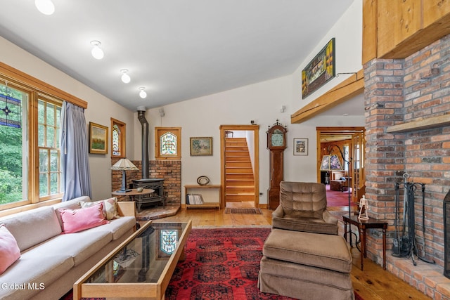 135 Willow St, Guilderland, NY 12084 - living room featuring a wood stove, wood-type flooring, vaulted ceiling, and stairway