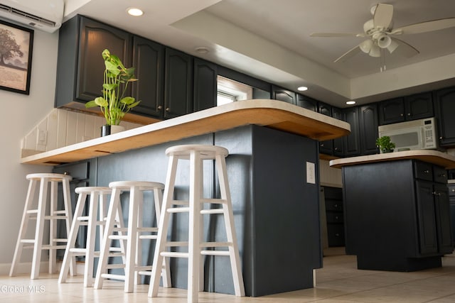 367 Buel Rd, Canajoharie, NY 13317 - kitchen featuring white microwave, an AC wall unit, ceiling fan, recessed lighting, and light tile patterned flooring