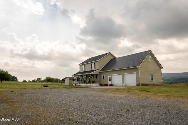 367 Buel Rd, Canajoharie, NY 13317 - view of front of house featuring gravel driveway, a porch, an attached garage, and a metal roof
