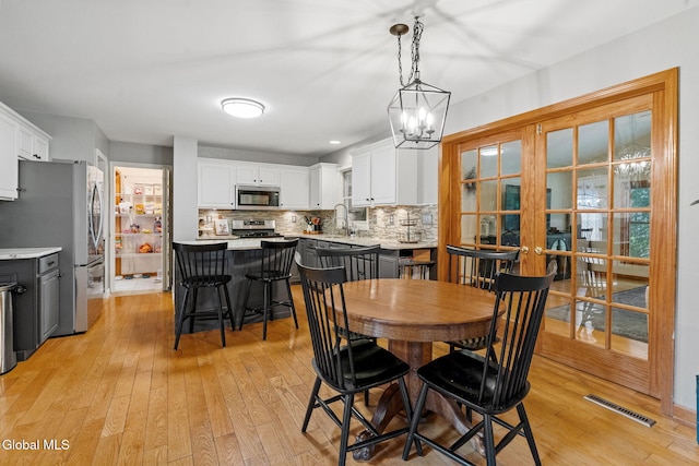 125 Halfmoon Dr, Guilderland, NY 12009 - dining space with light wood finished floors, french doors, and a chandelier