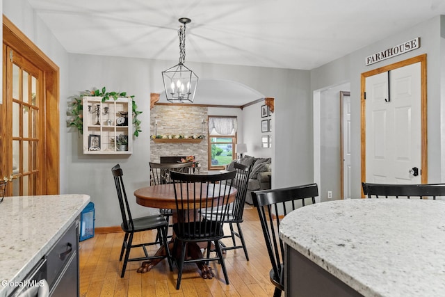 125 Halfmoon Dr, Guilderland, NY 12009 - dining space featuring light wood-style floors, arched walkways, a chandelier, and a fireplace