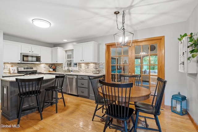 125 Halfmoon Dr, Guilderland, NY 12009 - kitchen featuring light wood-type flooring, backsplash, stainless steel appliances, white cabinetry, and a breakfast bar area