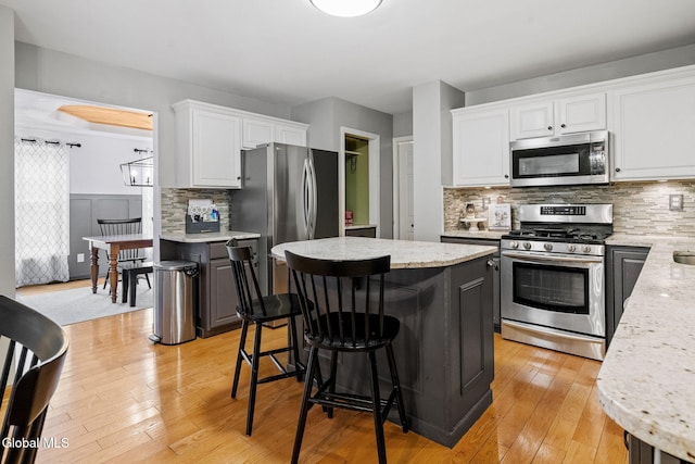 125 Halfmoon Dr, Guilderland, NY 12009 - kitchen with appliances with stainless steel finishes, a center island, tasteful backsplash, white cabinetry, and light wood-type flooring