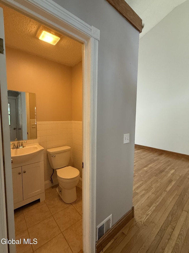 5 Crowsnest Ct, Halfmoon, NY 12188 - half bathroom with vanity, wood finished floors, a wainscoted wall, and tile walls