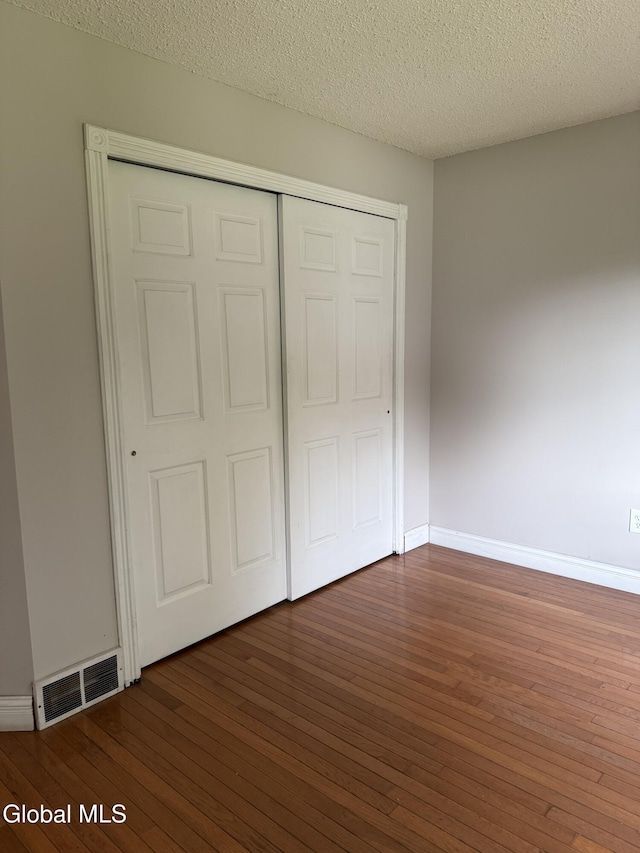 5 Crowsnest Ct, Halfmoon, NY 12188 - unfurnished bedroom with wood-type flooring, a textured ceiling, and a closet