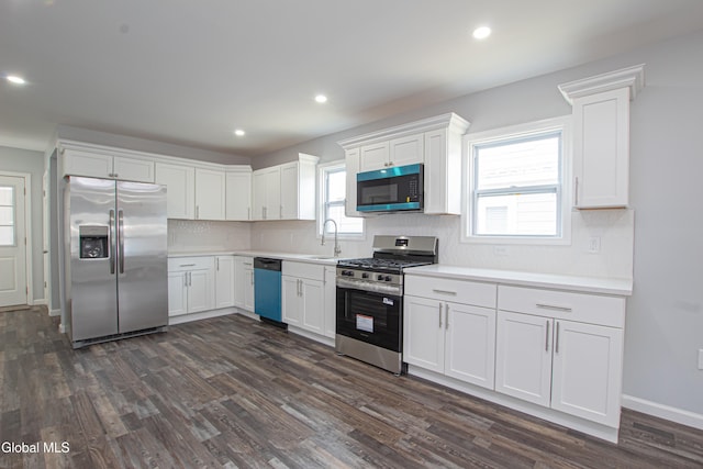 1628 Hawthorne St, Schenectady, NY 12303 - kitchen featuring appliances with stainless steel finishes, decorative backsplash, white cabinets, dark wood-style floors, and light countertops