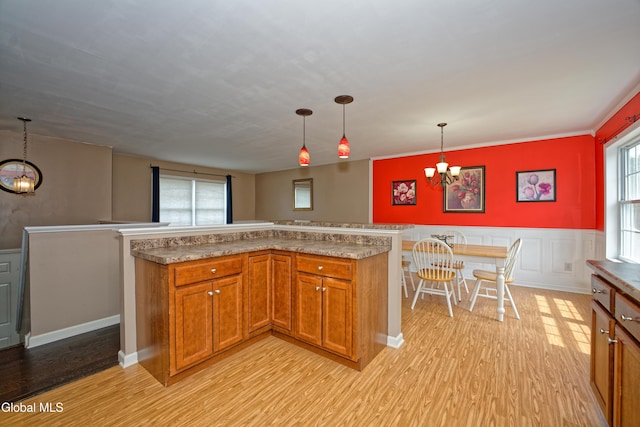 50 Sandy Ln, Bethlehem, NY 12158 - kitchen with a chandelier, brown cabinetry, light wood-style flooring, and a wainscoted wall