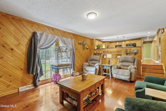 145 Sylvia Ln, Rotterdam, NY 12306 - living area with wood walls, light wood finished floors, and a textured ceiling