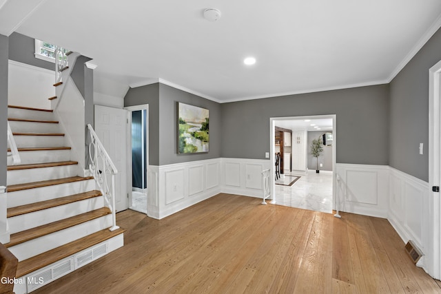 84 Glenwood Ave, Queensbury, NY 12804 - spare room featuring light wood finished floors, wainscoting, stairway, crown molding, and a decorative wall