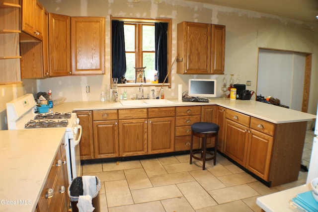 135 Glenwild Rd, Providence, NY 12850 - kitchen with white gas range, a peninsula, brown cabinetry, and light countertops